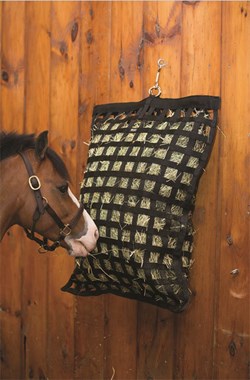 Bay horse eating hay through a small hole hay net to slow down & moderate his hay intake.