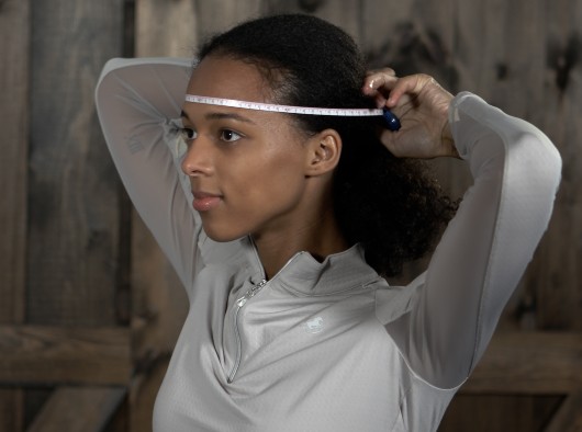 Woman measuring her head with a soft tape measurer.