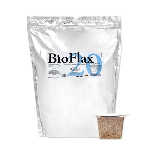 A horse happily grazing in a lush green pasture, with a bottle of BioFlax 20 supplements nearby. The sun is shining and the horse appears healthy and content